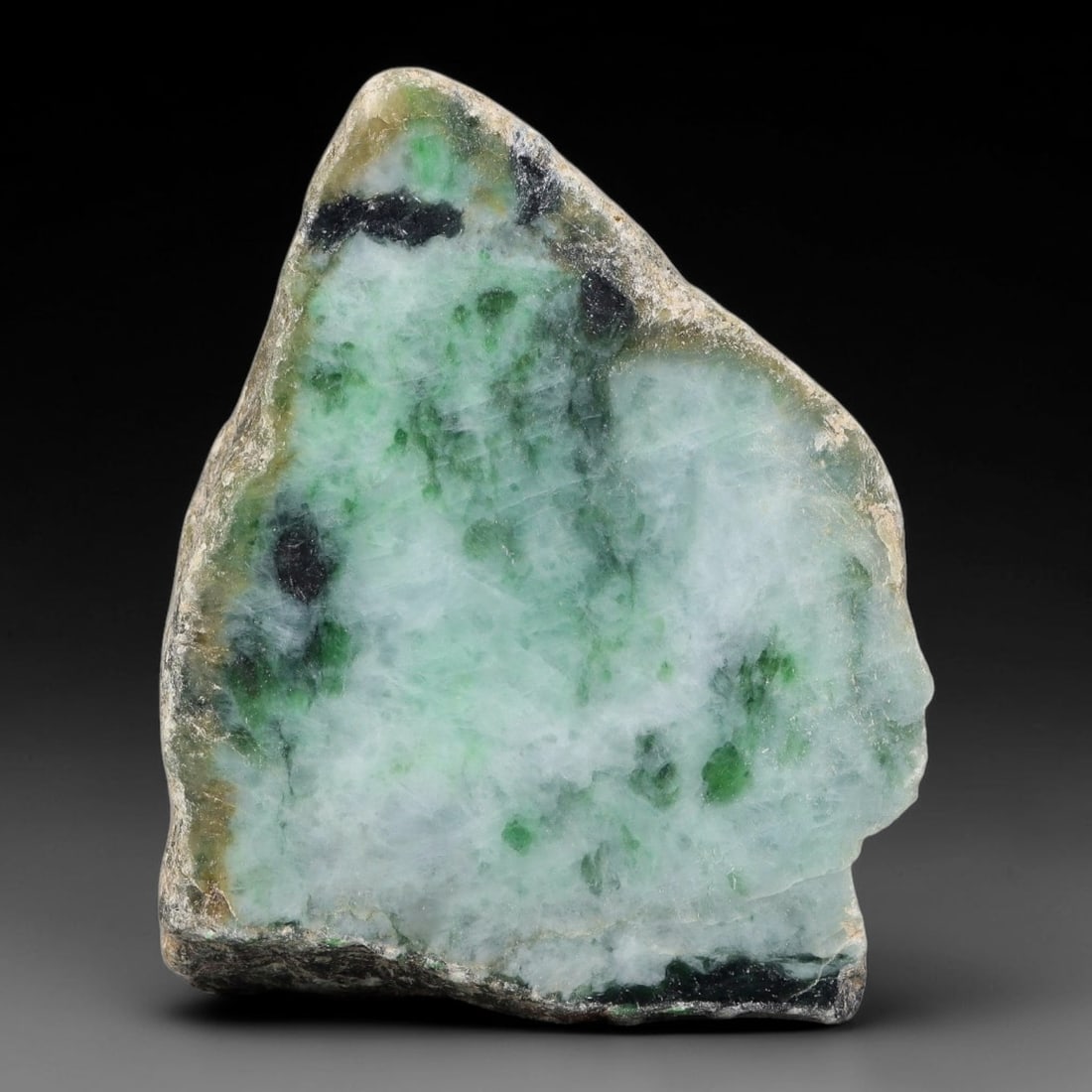 510ct Natural Type A Burmese Speckled Green Black Inclusion Jadeite Jade Sliced Rough, 49YN: This specimen is a natural split rough stone of untreated Type A Burmese jadeite, retaining rugged weathered host rock skin on its reverse side while its polished cut face displays translucent pale mi