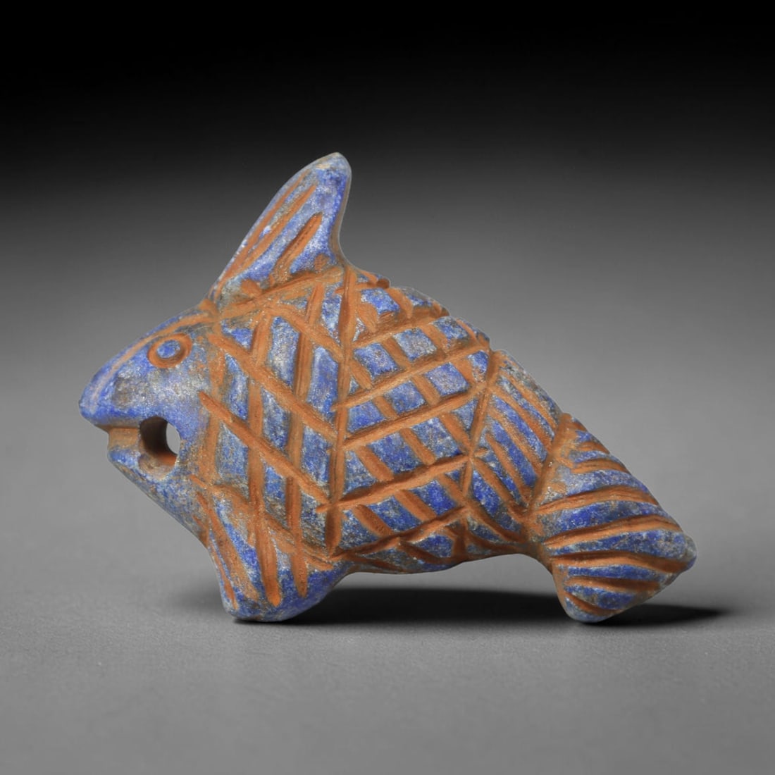 Ancient Lapis Lazuli Fish - Near Eastern Carved Animal Amulet, 29WT: Formed from natural lapis lazuli stone, this stylized fish figurine bears densely incised crisscross linework replicating scaled texture across its full body, with defined detailing for fins, tail and