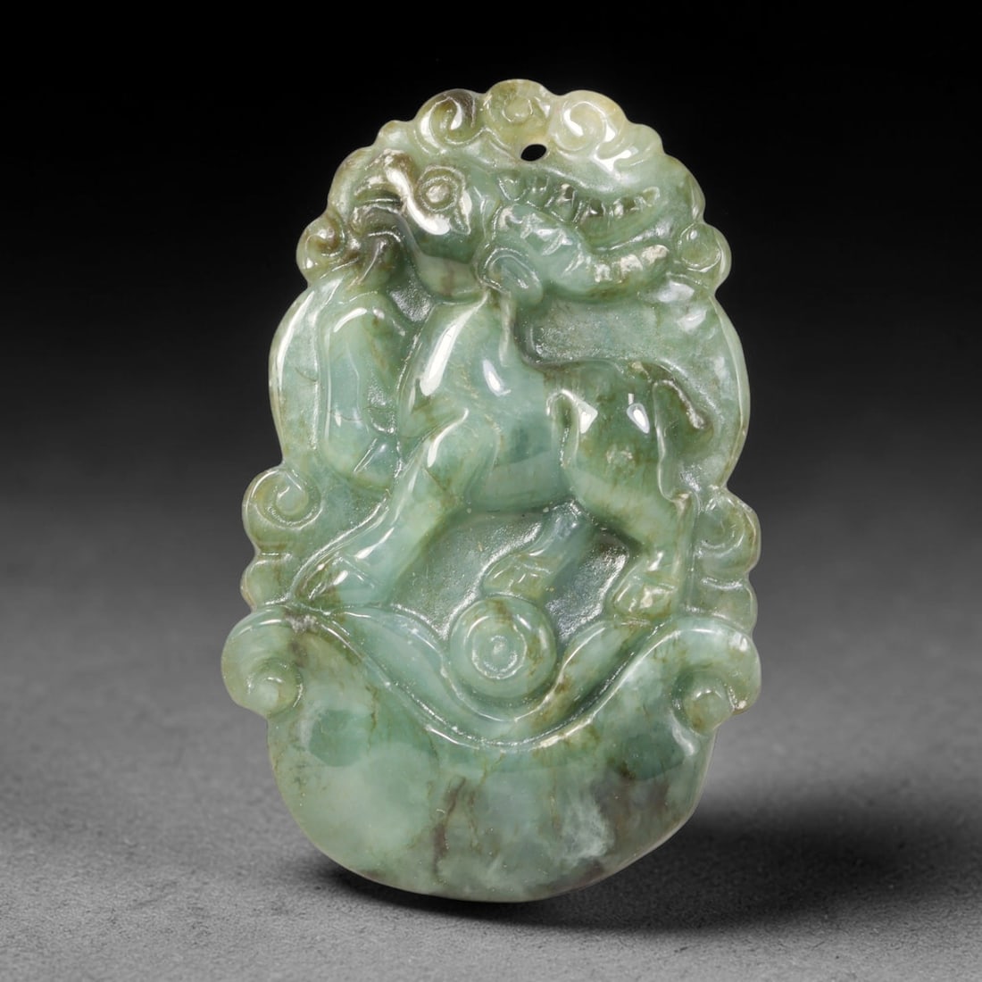 Natural Burmese Type A Jadeite Jade Carved Ox Pendant, 89XZ: Relief carved pendant worked from untreated natural Burmese Type A jadeite, featuring muted teal green stone interspersed with dark brown mineral veining and natural internal stone markings. The carvi