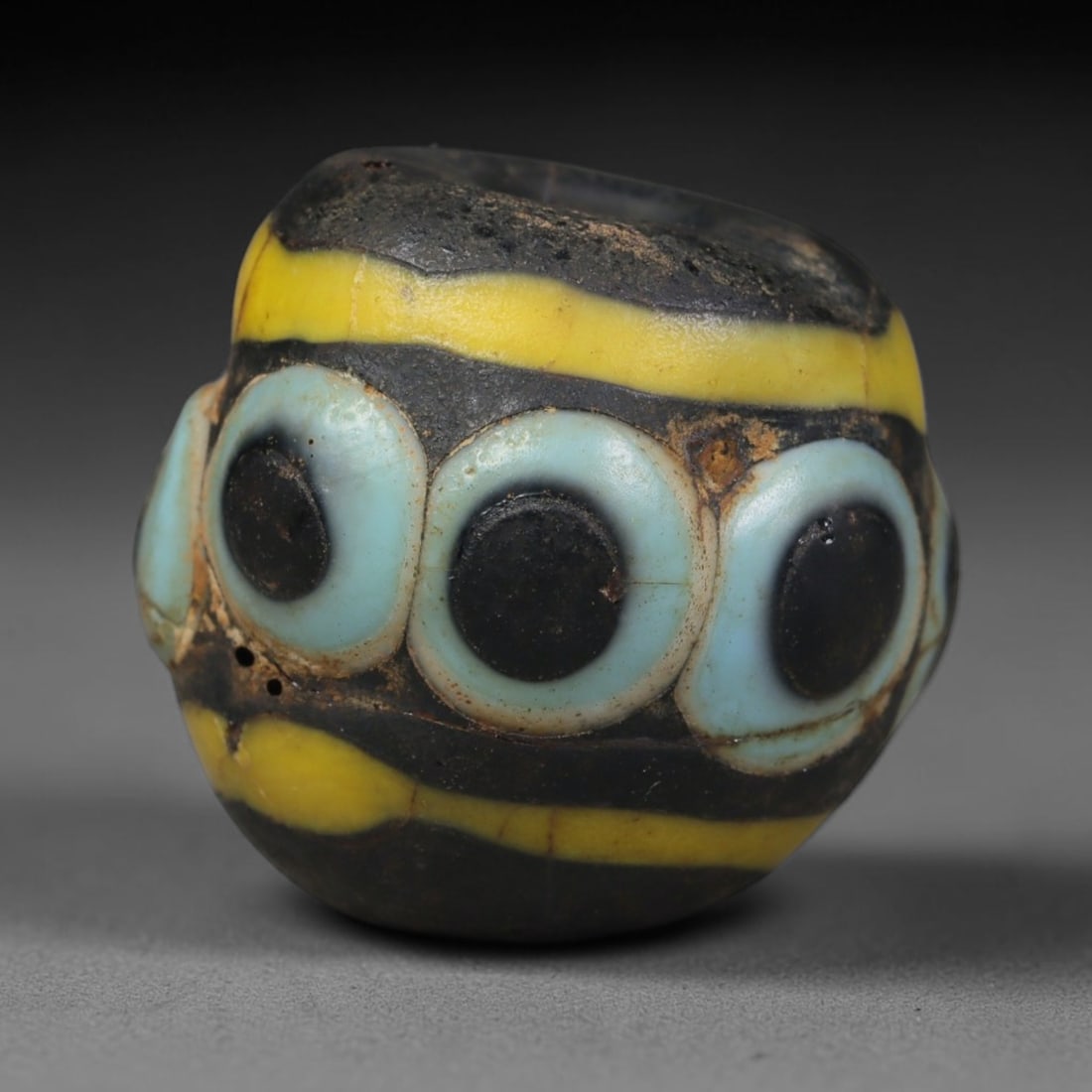 Ancient Islamic Hand Crafted Glass Bead Talisman, 24XD: Miniature antique wearable bead formed from hand-worked glass material, originating from ancient Islamic period glassmaking traditions across the Near East and North African cultural spheres. Glass wa