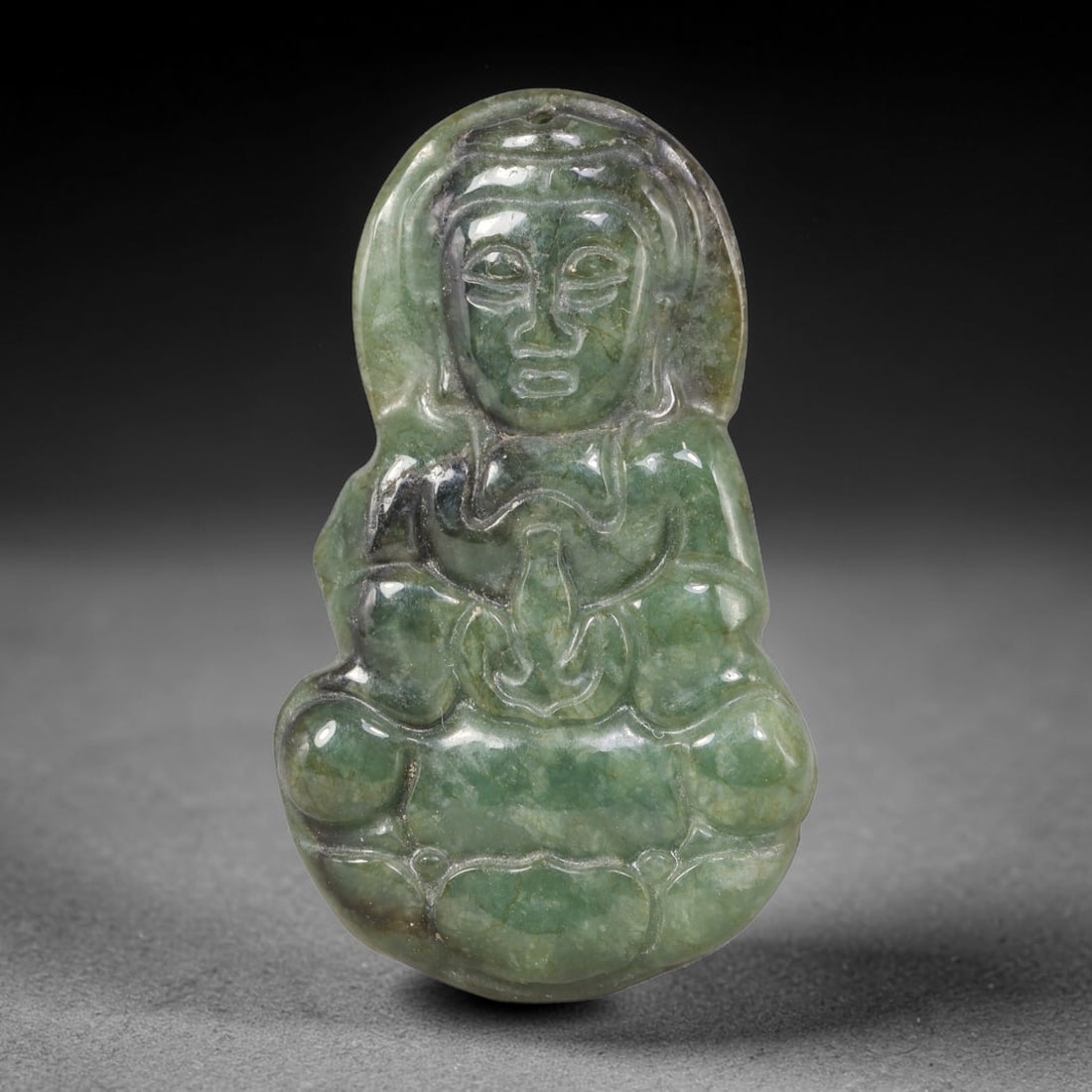 Natural Burmese Type A Jadeite Jade Seated Guanyin Pendant, 87XZ: Hand-carved talisman rendered from untreated natural Burmese Type A jadeite, featuring mottled forest green stone interspersed with dark mineral streaks and natural internal inclusions. The relief car