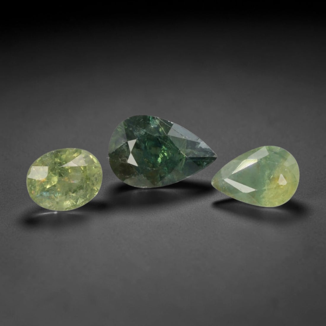 2.89 Carats Color-Change Green Sapphire Parcel - Natural Madagascan Stones, 79XC: This trio of loose sapphires showcases a captivating range of green hues, from soft lime and mint to deep forest green with subtle teal undertones. The set includes one oval and two pear cuts, each fa