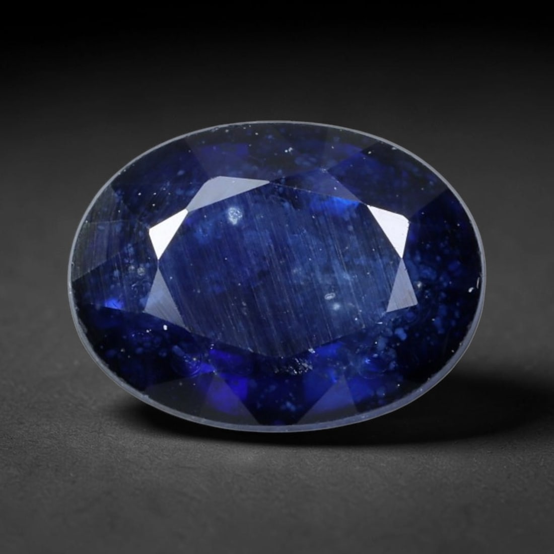 1.51 Carats Deep Royal Blue Sapphire Oval - Natural Ceylon Stone, 80XB: This singular oval-cut sapphire, measuring 7.2 x 5.5 x 3.8 mm, displays a rich, saturated royal blue hue reminiscent of deep ocean waters and midnight skies. Its faceting captures light to reveal subt