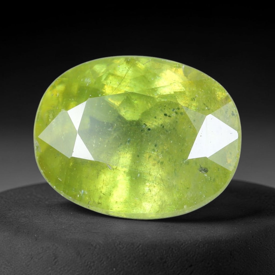 3.47 Carats Lime Green Oval Sphene - Natural Loose Gemstone, 84XB: This vibrant oval sphene dazzles with a luminous lime-green hue, brought to life by the gemstone's exceptional light-dispersing properties. Measuring 9.9x7.9x5.3mm, the faceted cut unlocks sphene's si