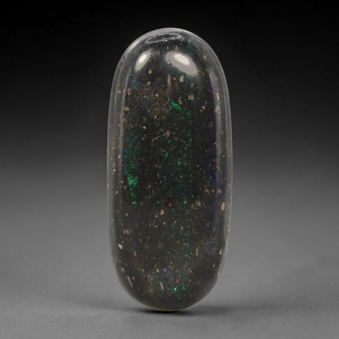 16.82 Carats Australian Matrix Opal Elongated Oval Cabochon - Natural Stone, 68XB: This singular elongated oval cabochon matrix opal, measuring 30.2 x 13.4 x 5.7 mm, features a deep, dark host matrix with concentrated, vivid opal flashes. The polished surface reveals striking streak