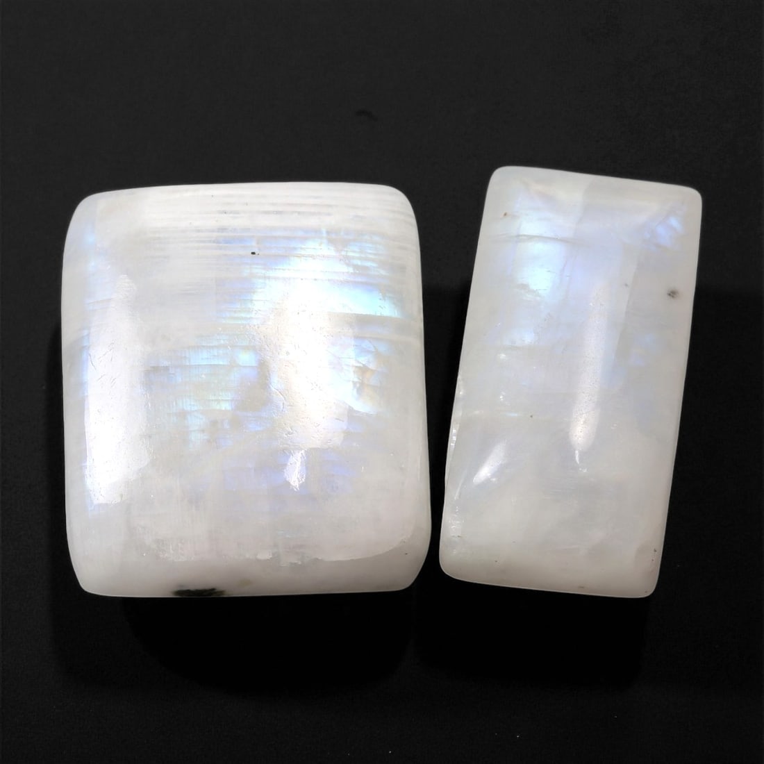 45.45 Carats Silvery Blue Moonstone Pair - Natural Rectangular Cabochons, 60XC: This luminous moonstone pair captivates with a soft, silvery glow and vibrant blue adularescence that shimmers across their curved surfaces. Set against a milky white base, the internal sheen rolls ge