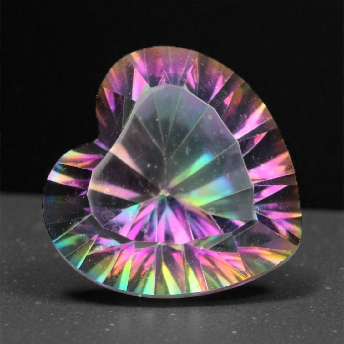 3.65 Carats Iridescent Mystic Topaz - Heart Cut Natural Stone , 18WC: Radiating a kaleidoscope of vibrant hues, this heart-cut mystic topaz dazzles with shifting flashes of violet, teal, gold, and magenta. Its dramatic faceting and highly polished surface create a mesme