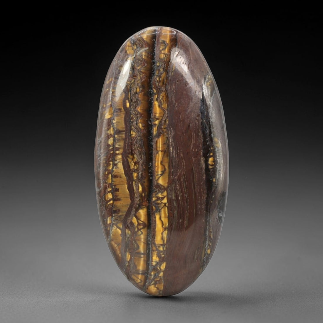 66.76 Carats Golden Banded Tiger Eye Cabochon Oval - Natural South African Stone, 96XB: This singular oval cabochon tiger eye, measuring 47.5 x 23.7 x 5.8 mm, displays dramatic vertical banding of rich golden-yellow and deep brown hues, interspersed with subtle chatoyant fibers that crea