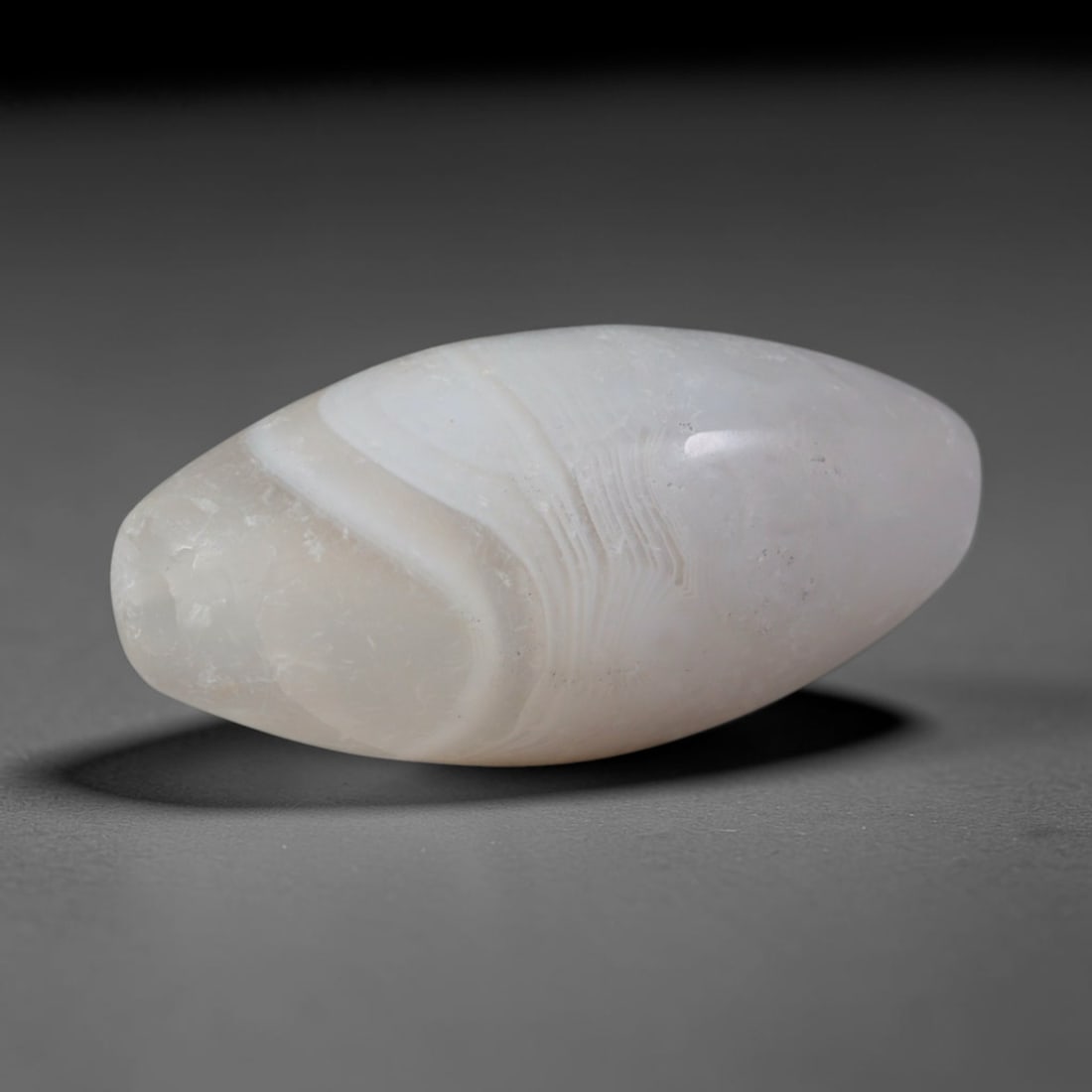 Ancient Predynastic & Pharaonic Egyptian Banded Agate Bullet Bead (4000 BCE-30 CE), 53XD: This antique bullet-shaped banded agate bead originates from Predynastic & Pharaonic Egyptian Civilization, an ancient Northeast African culture that crafted chalcedony beads for funerary amulets, bro