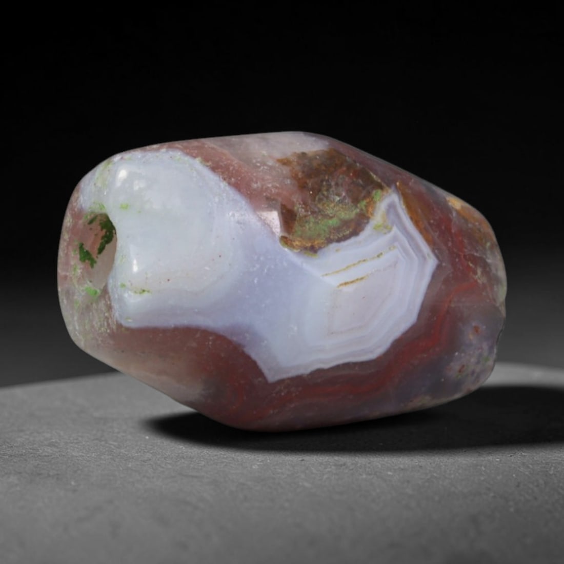 Ancient Mesopotamian Red Banded Agate Faceted Mini Barrel Amulet Bead (1200-500 BCE), 36XD: This antique hand-faceted banded agate bead originates from ancient Mesopotamian hardstone workshops, crafted as compact protective talismans for elite personal adornment and ritual burial assemblages