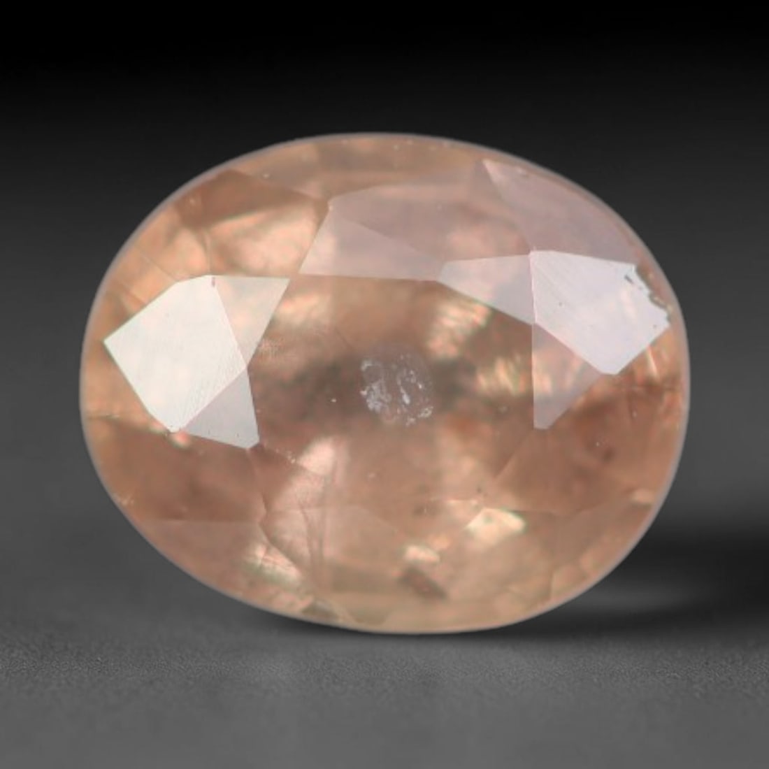 0.36 Carats Natural Peach Sapphire Oval Faceted Loose Gemstone, 66XV: Natural peach-toned corundum sapphire fashioned as an oval faceted loose gemstone, cut with mixed brilliant facets to enhance light reflection. The stone holds a soft warm pale peach hue, with subtle 