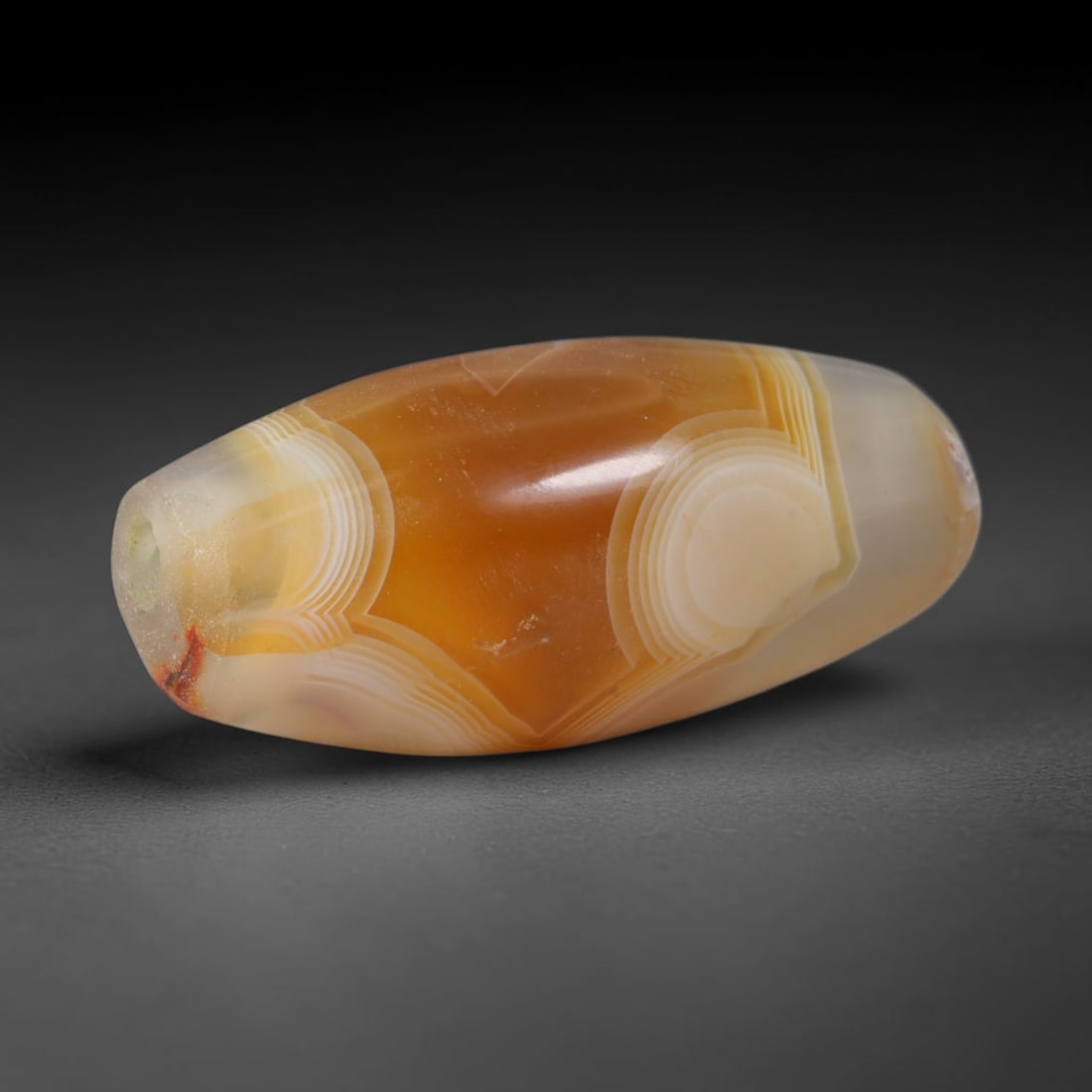 Ancient Sasanian Persian Banded Carnelian Agate Barrel Bead (224-651 CE), 95XD: This antique banded carnelian agate barrel bead originates from the Sasanian Persian Empire, famed elite hardstone artisans who crafted symmetrical patterned agate talismans for Zoroastrian nobility a