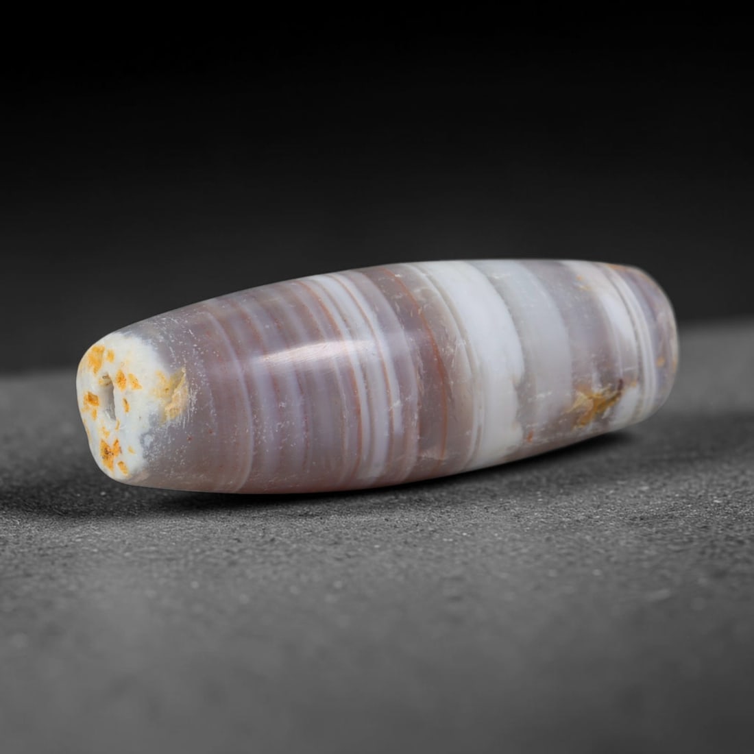 Ancient Bactrian Banded Lavender Chalcedony Elongated Barrel Trade Bead (250 BCE - 100 CE), 9XV: This antique horizontally banded chalcedony barrel bead originates from Greco-Bactrian Central Asian craft workshops, famed suppliers of fine layered agate talismans moving along early Silk Road route
