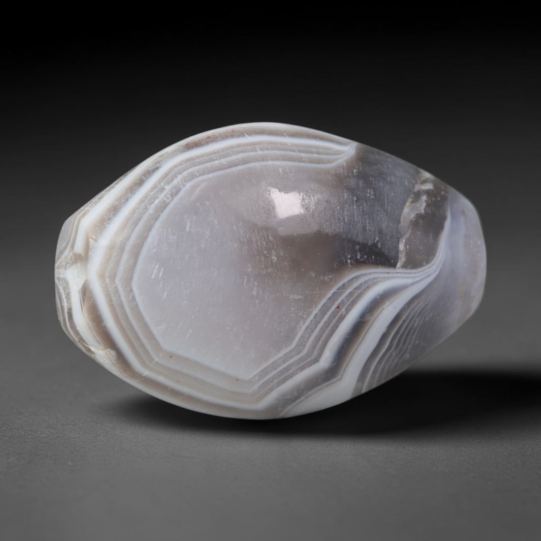 Ancient Sasanian Persian Grey Banded Agate Broad Barrel Amulet Bead (224-651 CE), 12XV: This antique wide barrel banded agate bead originates from Sasanian Iranian stoneworking ateliers, famed for symmetrical layered chalcedony talismans worn by Zoroastrian elites and traded westward to 