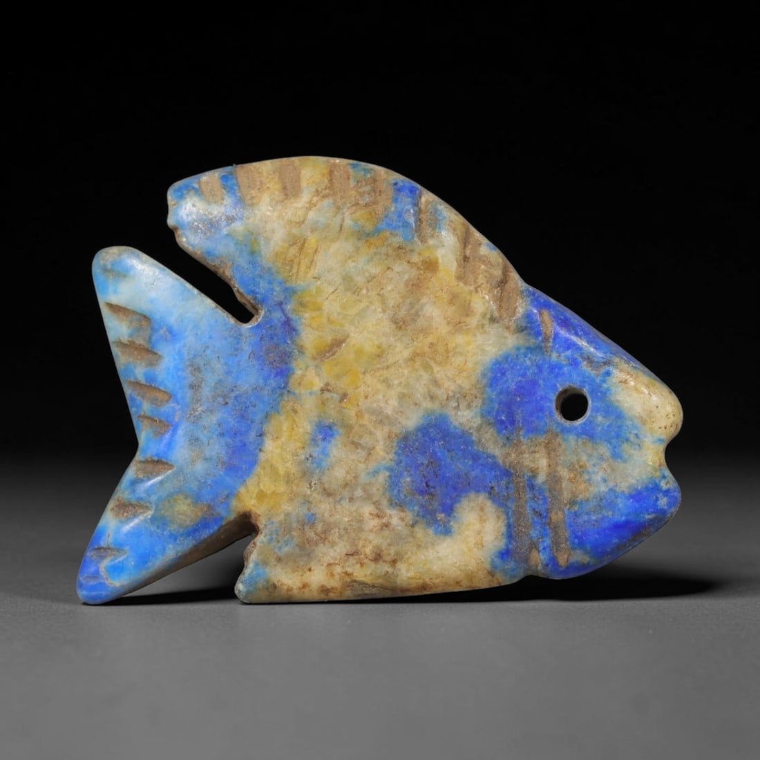 Ancient Lapis Lazuli Fish - Near Eastern Animal Amulet, 28WT: Carved from variegated lapis lazuli with natural pale calcite and golden pyrite inclusions throughout the blue stone matrix, this piece is rendered in stylized fish form characteristic of ancient Near