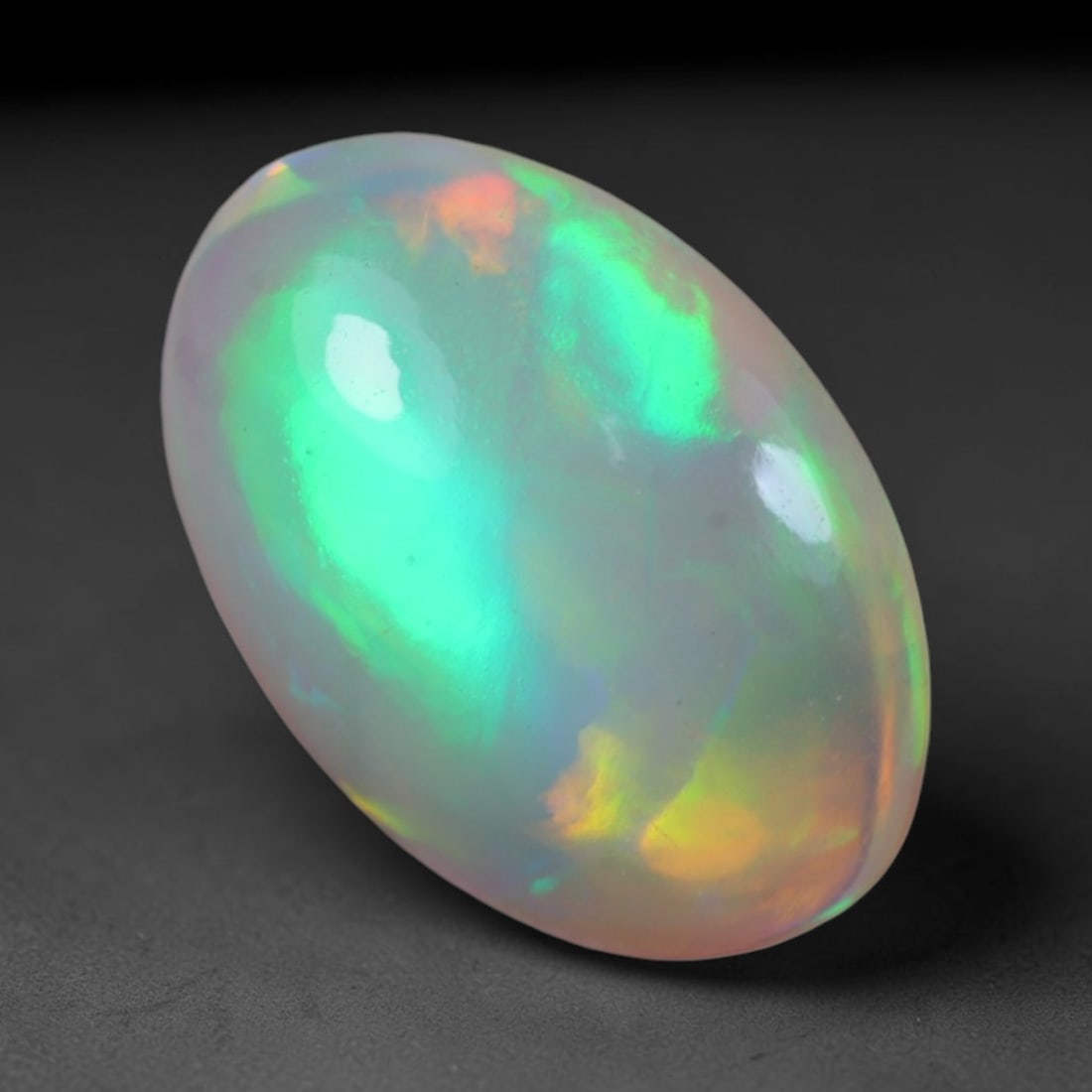 1.94 Carats Natural Ethiopian Welo Opal Oval Cabochon Loose Gemstone, 43XV: Natural Ethiopian Welo opal polished oval cabochon loose gemstone, luminous translucent milky white base stone with vivid multi-hued play-of-color featuring bright emerald green, lime yellow, soft blu