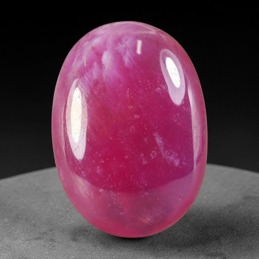 26.26 Carats Natural Madagascar Vivid Fuchsia Pink Heated Ruby Oval Cabochon Loose Gemstone, 93WC: This saturated fuchsia pink ruby cabochon carries rich deep magenta-pink tones blended evenly across its smoothly polished domed surface, dotted with fine natural mineral speckles and faint crystallin