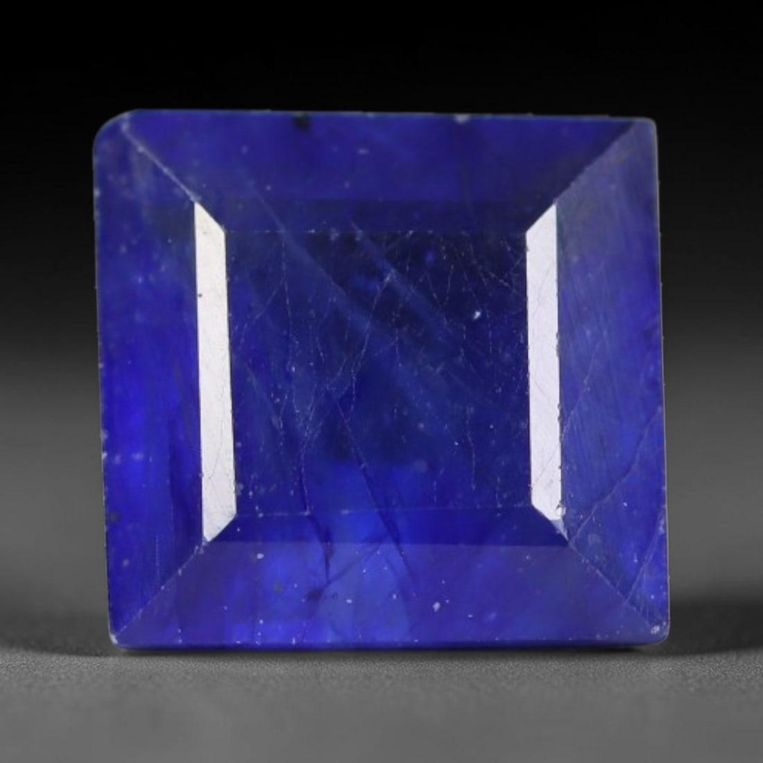 2.15 Carats Royal Blue Sapphire Square Emerald Cut Loose Gemstone, 34WS: This neat square emerald cut sapphire showcases deep, saturated royal blue color, enhanced by clean reflective step facets. Natural internal fine fissures and scattered tiny mineral specks can be obse