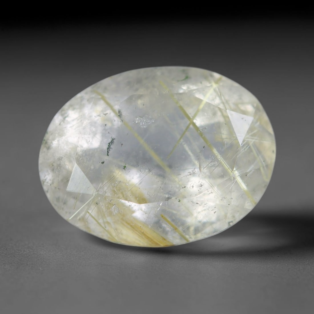 7.94 Carats Natural Crossed Golden Rutilated Quartz Oval Faceted Loose Gemstone, 19WS: This generously sized oval faceted rutilated quartz features a clear translucent crystal base threaded with striking intersecting golden rutile needle strands, accented by tiny dark green mineral flec
