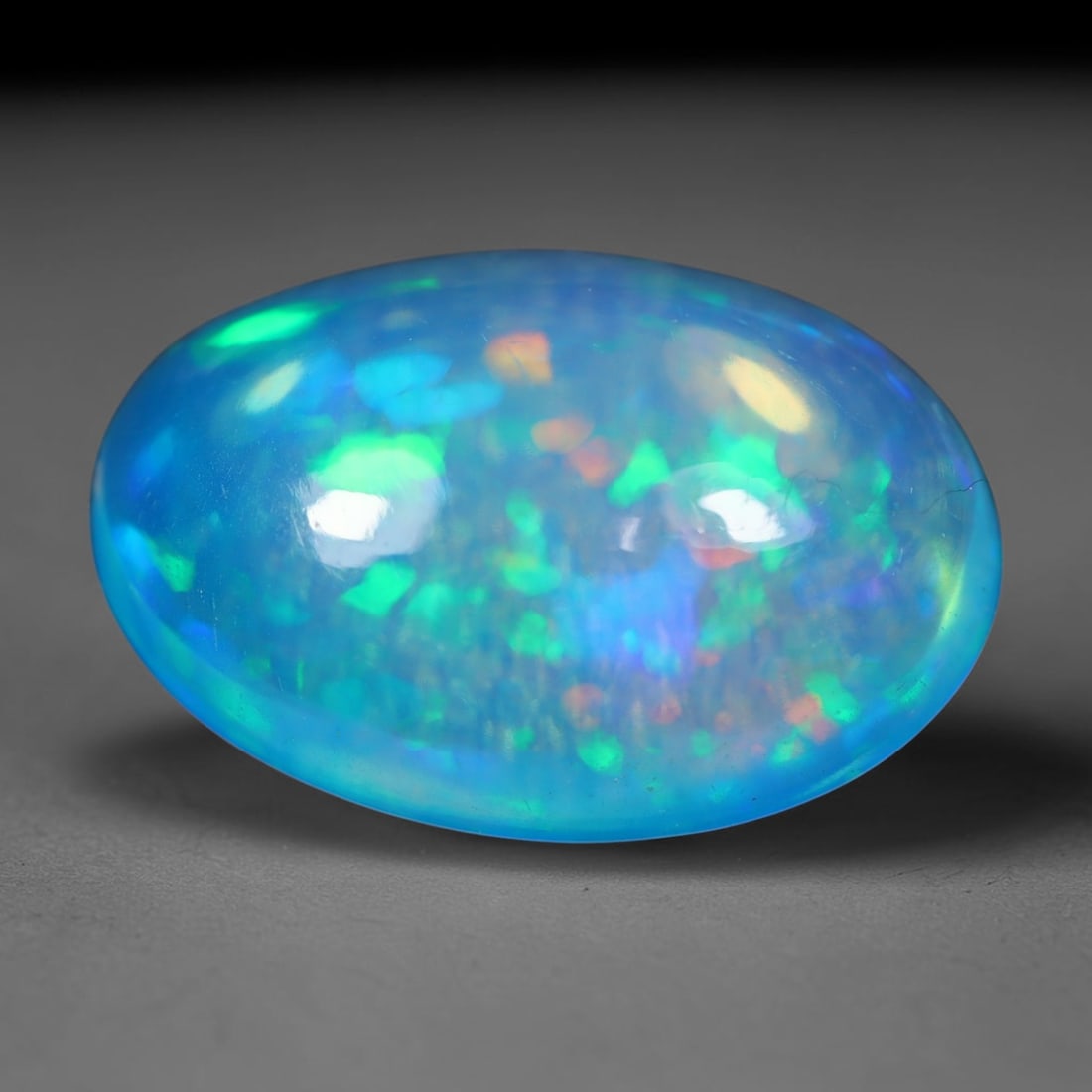 3.83 Carats Natural Ethiopian Welo Vivid Sky Blue Oval Cabochon Opal Loose Gemstone, 99WS: This smooth domed oval cabochon Ethiopian Welo opal features a rich translucent vibrant sky-blue base, covered with scattered mosaic play-of-color including neon green, golden yellow, soft orange and 