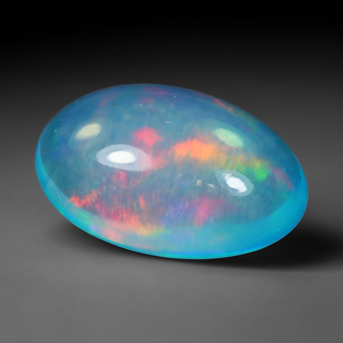 4.63 Carats Natural Ethiopian Welo Bright Blue Oval Cabochon Opal Loose Gemstone, 95WS: This sleek elongated oval cabochon Ethiopian Welo opal features a vivid translucent sky-blue base stone, covered with striking broad play-of-color including fiery red, tangerine orange, lime green and