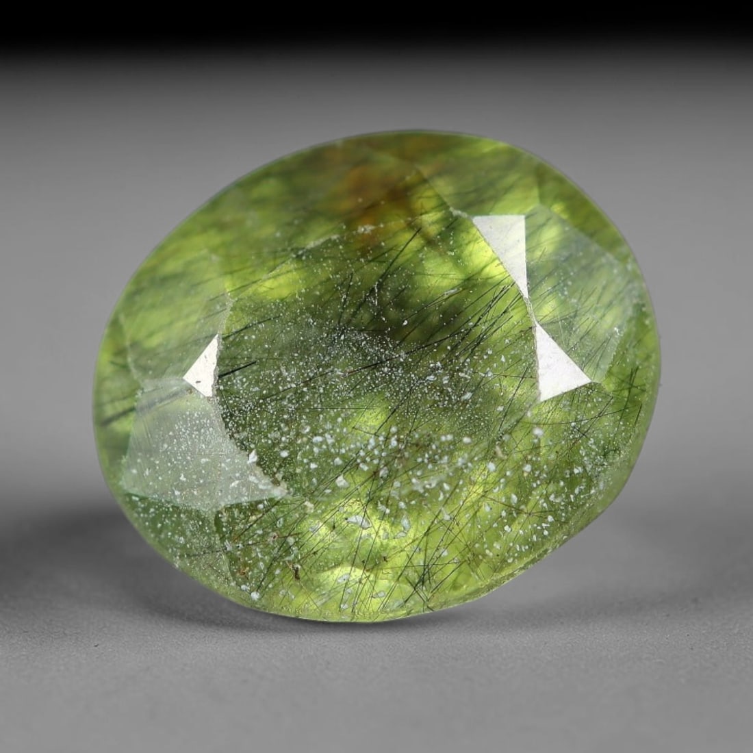 3.11 Carats Natural Green Rutilated Peridot Oval Faceted Loose Gemstone, 73WS: This classic oval faceted peridot features a soft translucent pale olive green crystal filled with striking clusters of dark brown and black rutile needle silk that crisscross throughout the stone, wi