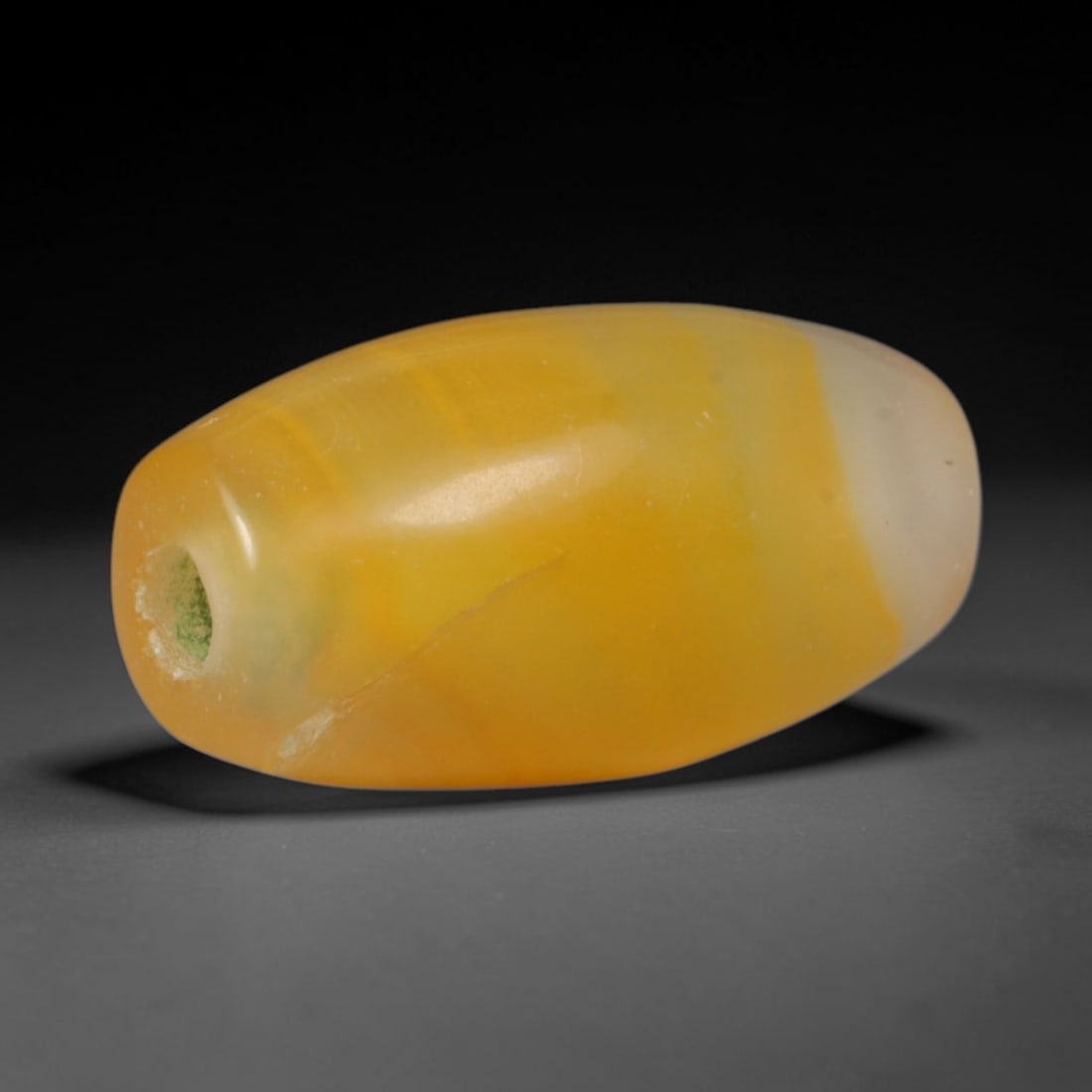 Ancient Indo-Scythian Golden Honey Carnelian Two-Tone Oval Barrel Trade Bead (150 BCE - 400 CE),: This warm gradient carnelian barrel bead hails from Indo-Scythian Central Asian stoneworking traditions, crafted as luminous protective talismans prized by nomadic nobles and trans-Asian caravan trade