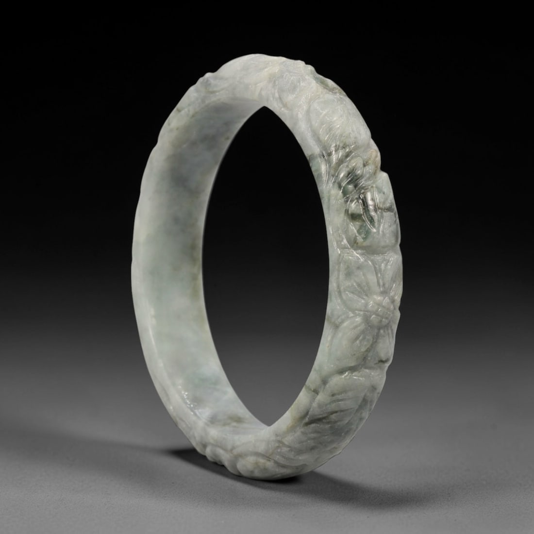 Natural Burmese Type A Carved Jadeite Jade Bangle Bracelet, 42ZL: A fine jadeite bangle of flattened circular form, masterfully carved in relief with a continuous band of chrysanthemum blossoms and scrolling foliate motifs. The stone exhibits a translucent pale gree
