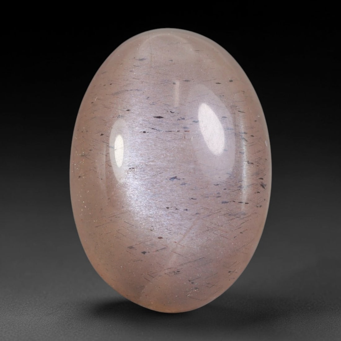 11.68 Carats Natural Ceylon Peach Inclusions Moonstone Oval Cabochon Loose Gemstone, 86WS: This soft peach-toned Ceylon moonstone oval cabochon features a translucent pale blush base laced with fine dark fibrous mineral inclusions distributed evenly throughout the feldspar matrix, paired wi