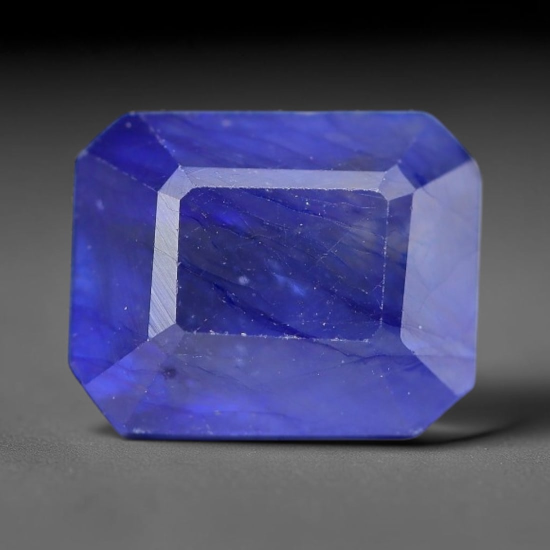 4.40 Carats Royal Blue Sapphire Emerald Cut Loose Gemstone, 7WJ: This sharp emerald rectangular faceted sapphire features an intense deep royal blue hue, brought to vivid life by crisp step-cut facets. Natural fine fissures and scattered tiny mineral micro-inclusio