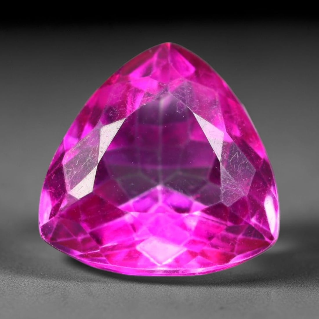 6.85 Carats Natural Vivid Pink Topaz Trillion Faceted Loose Gemstone, 9WS: This brilliant trillion faceted pink topaz displays vivid saturated hot pink color glowing through sharp polished facets, with faint minor natural surface fine lines visible inside the transparent cry