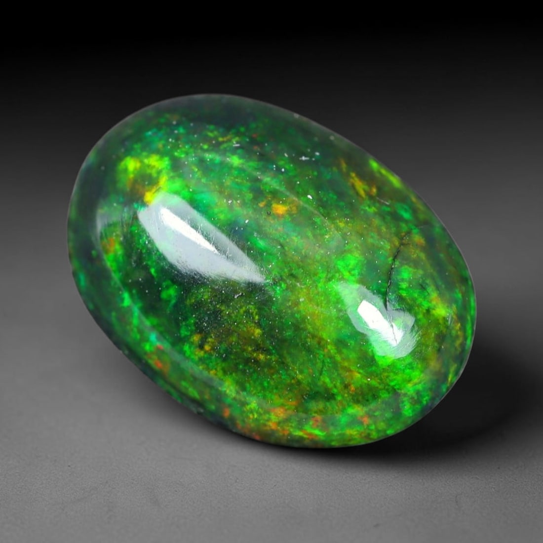 1.39ct Natural Ethiopian Welo Black Smoked Opal Cabochon Loose Gemstone, 95WP: This fully polished Ethiopian Welo opal features a dark smoked base with vivid, sweeping play-of-color shifting across its glossy dome surface, measured at 10.1x7.3x3.9mm. The black smoke treatment de