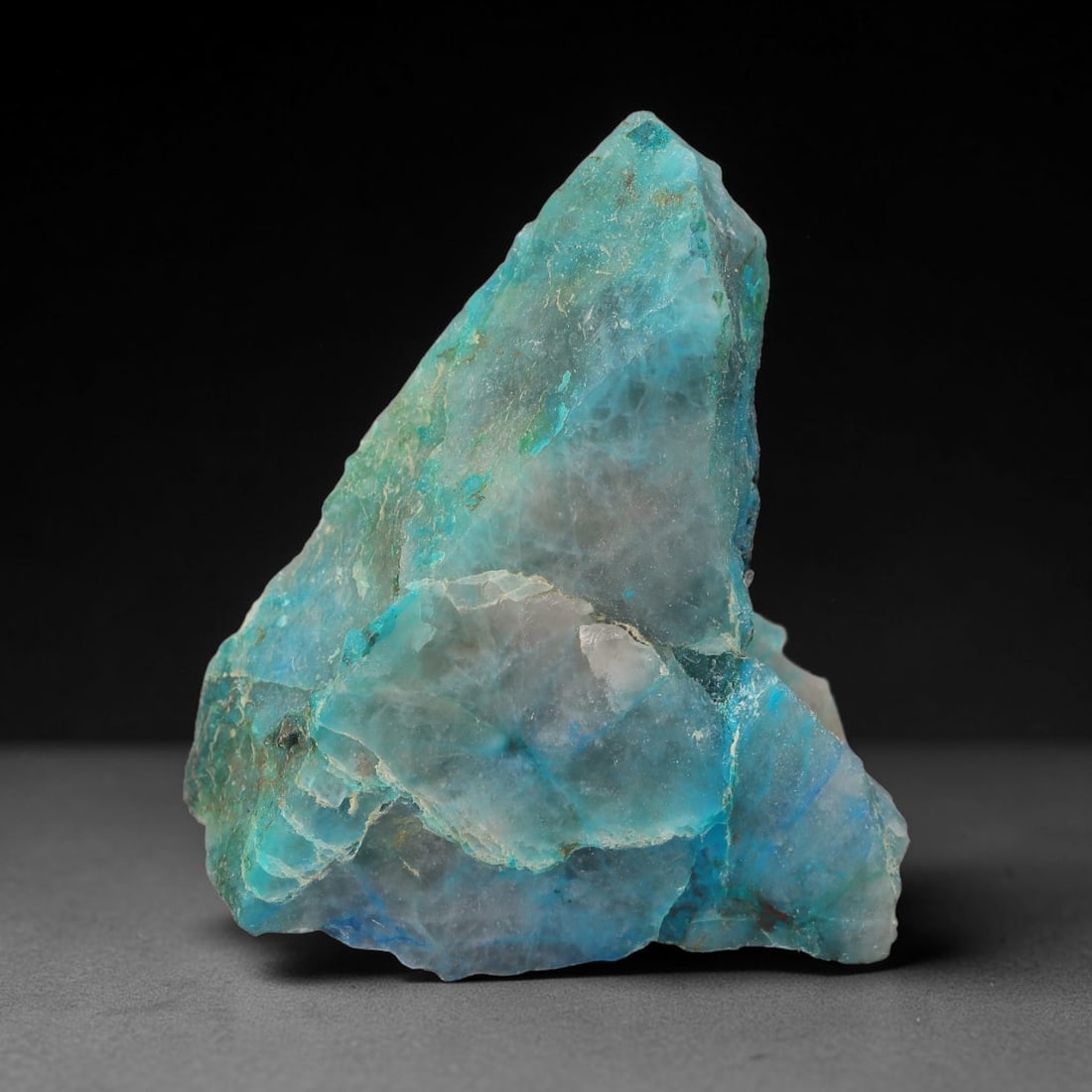 153ct Natural Peruvian Chrysocolla Polished Slab Rough, 60WV: This partial-polished chrysocolla slab features blended mineral matrix with smooth refined face and unaltered natural rugged edge across its 47x37x14mm elongated form, translucent mineral layers hold 