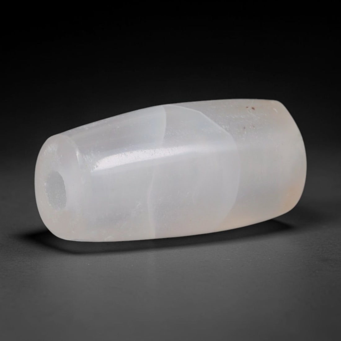 Ancient Central Asian Steppe Pale Milky Chalcedony Smooth Barrel Amulet Bead (800-200 BCE), 46XD: This antique translucent milky pale chalcedony barrel bead originates from Eurasian steppe nomadic stone carvers, who crafted understated monochrome hardstone talismans for tribal adornment and carava