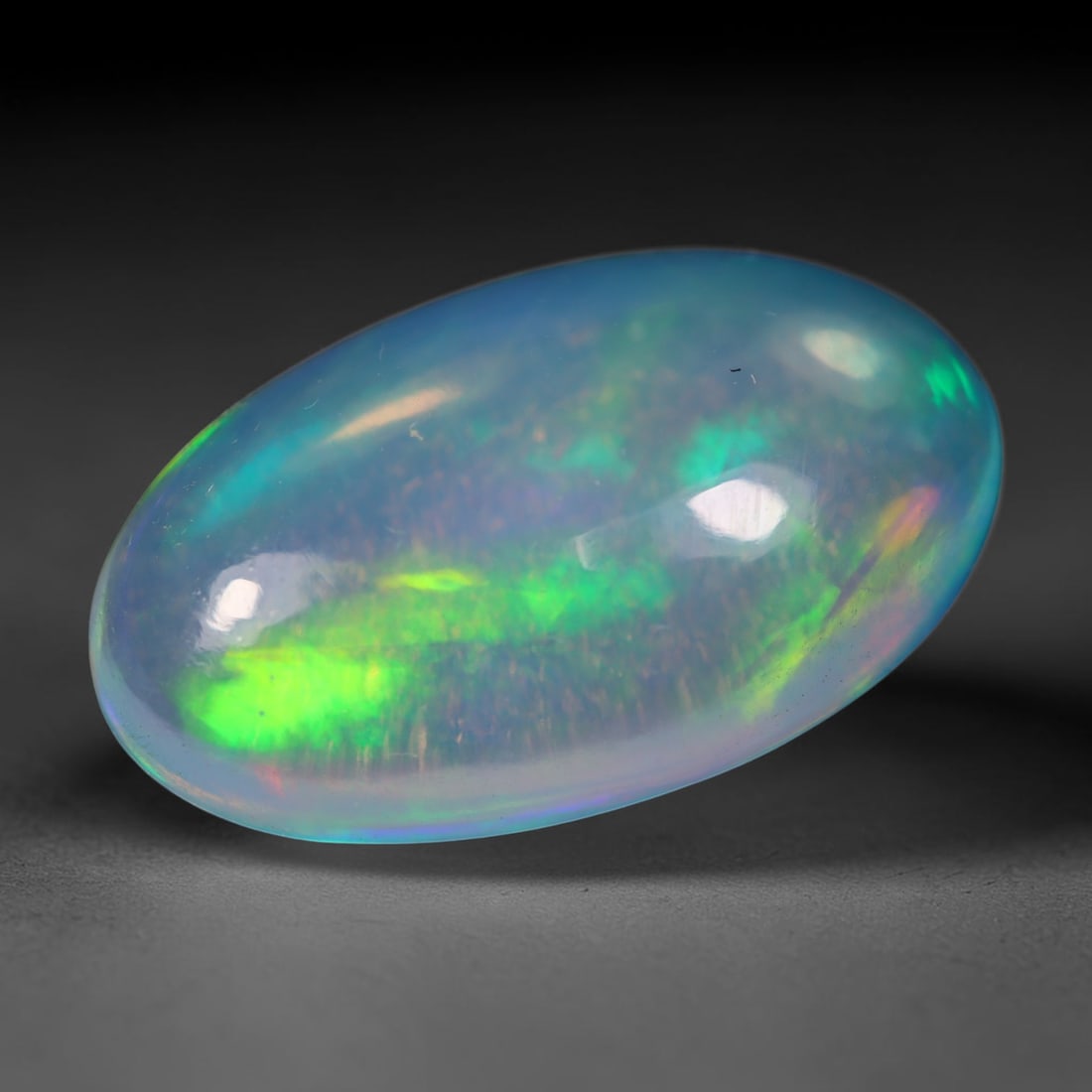 5.98 Carats Natural Ethiopian Welo Pale Blue Long Oval Cabochon Opal Loose Gemstone, 100WS: This slender elongated oval cabochon Ethiopian Welo opal carries a soft translucent pale sky-blue base, highlighted by bold swathes of neon lime green flash with faint golden yellow and subtle pink ir