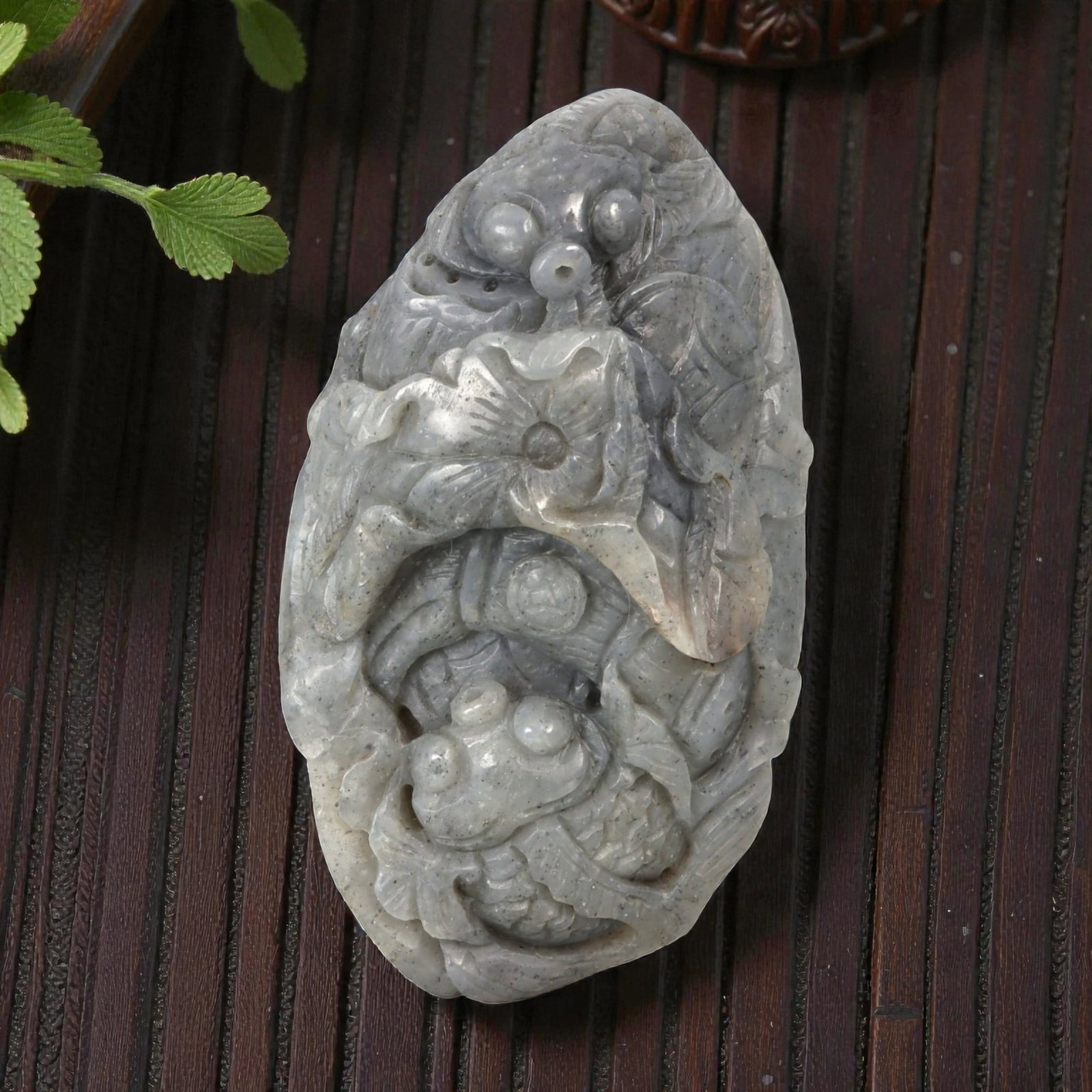 A Chinese Hetian Nephrite Jade Fish Carving Pendant, 19YB: Carved from pale grey nephrite jade with darker speckled inclusions and subtle tonal variation, the object is worked as a vertical composition featuring multiple fish arranged in a stacked and interlo