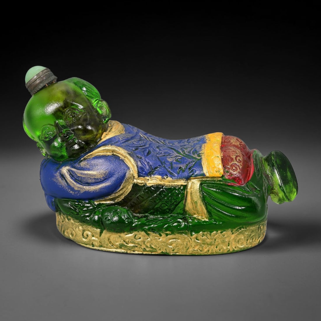 Vintage Chinese Liuli Glass Snuff Bottle - Reclining Sleeping Child, 80YF: This snuff bottle is moulded from translucent green liuli glass and crafted as a peacefully reclining sleeping child. The child's blue robe features embossed floral patterns highlighted with gilded tr