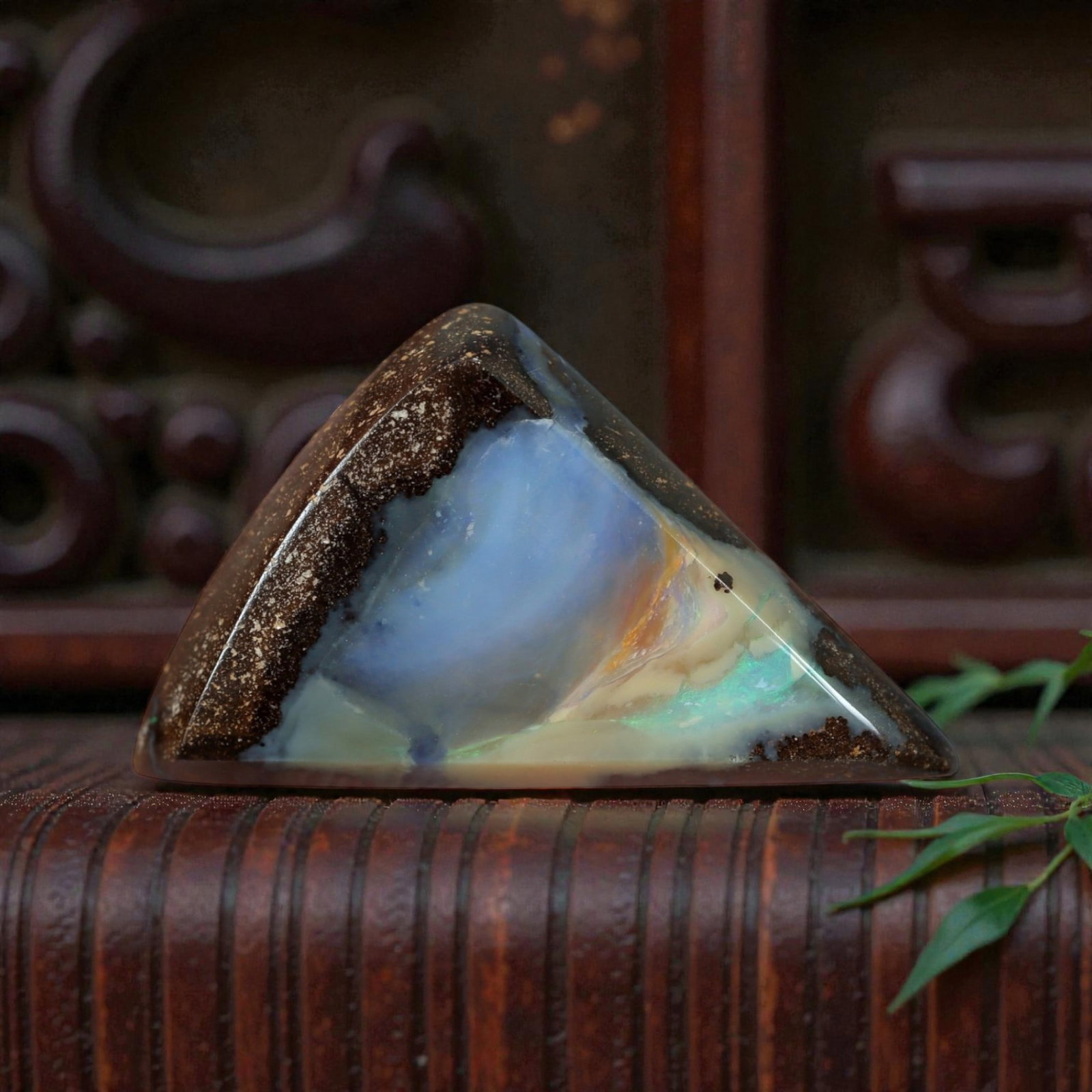 5.82 Carats Soft Blue and Iridescent Green Boulder Opal Cabochon - Natural Australian Stone, 46XM: This striking boulder opal cabochon features a smooth, triangular form with a rich brown ironstone matrix framing a luminous core of soft blue opal, accented by delicate iridescent green and golden fl