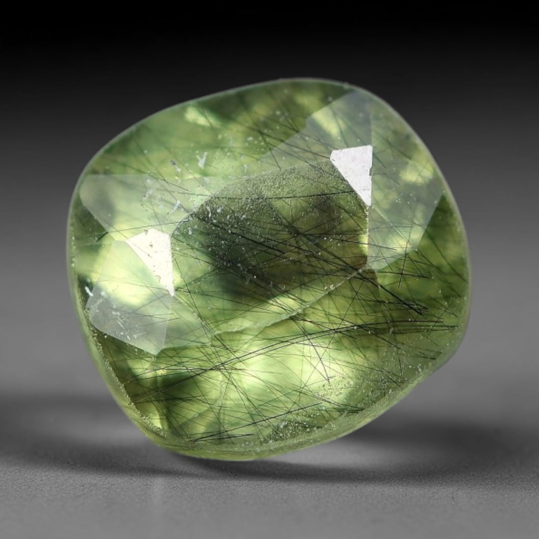 1.44 Carats Natural Green Rutilated Peridot Cushion Cut Loose Gemstone, 75WS: This soft cushion faceted peridot boasts a fresh translucent lime-green base densely threaded with delicate crisscross black rutile needle inclusions, dotted with tiny natural mineral micro specks acr