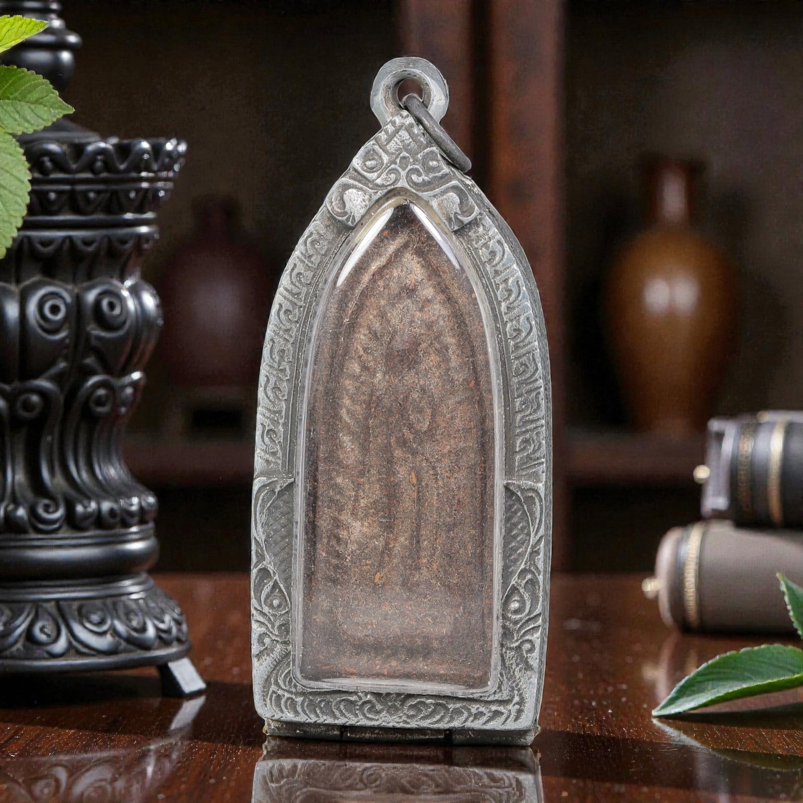 Thai Standing Buddha Amulet - Silver Tone Pendant, 52ZB: A Thai Buddhist amulet featuring a carved standing Buddha figure, housed in an elongated silver-tone metal casing with a glass-fronted enclosure. The amulet plaque displays a dark, patinated surface c