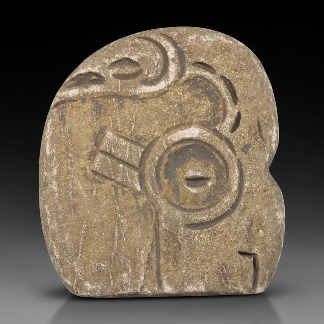 Ancient Medieval Near Eastern Tribal Stone Effigy, 85WT: Carved from weathered matte stone bearing faint natural fissuring, this rounded tribal effigy plaque is decorated with abstract incised circular, curved and linear motifs characteristic of medieval Ne