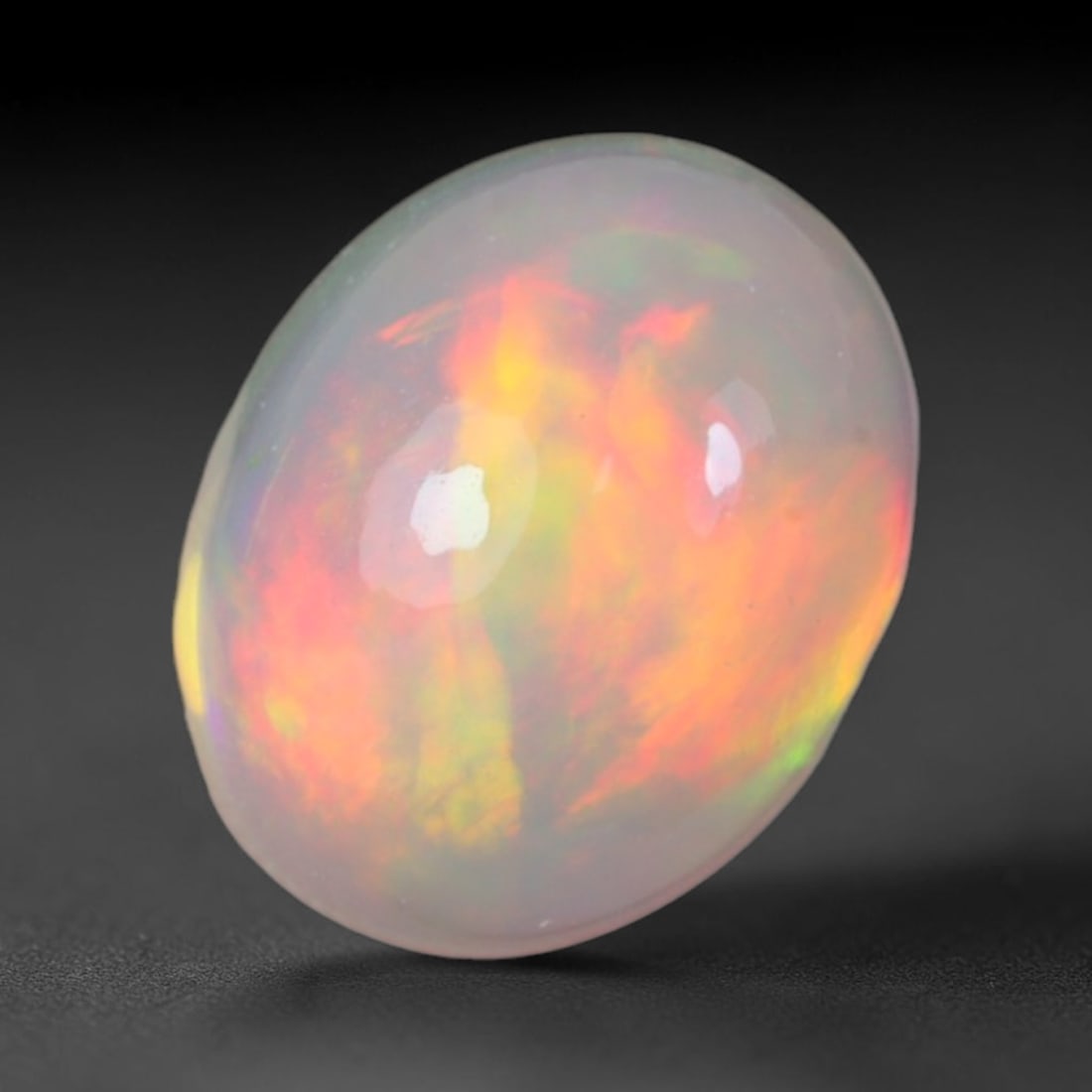1.90 Carats Natural Ethiopian Welo Opal Oval Cabochon Loose Gemstone, 55XV: Natural Ethiopian Welo opal polished oval cabochon loose gemstone, luminous translucent milky white base stone with vivid multi-hued play-of-color featuring bright emerald green, lime yellow, soft blu