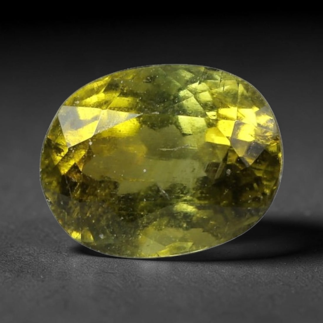 1.38 Carats Golden Olive Tourmaline Oval Cut - Natural Loose Gemstone, 64XC: This rich oval-cut tourmaline features a deep golden olive hue, evoking the warmth of aged amber or sunlit forest foliage. Its faceting creates a brilliant play of light, with subtle color variations 