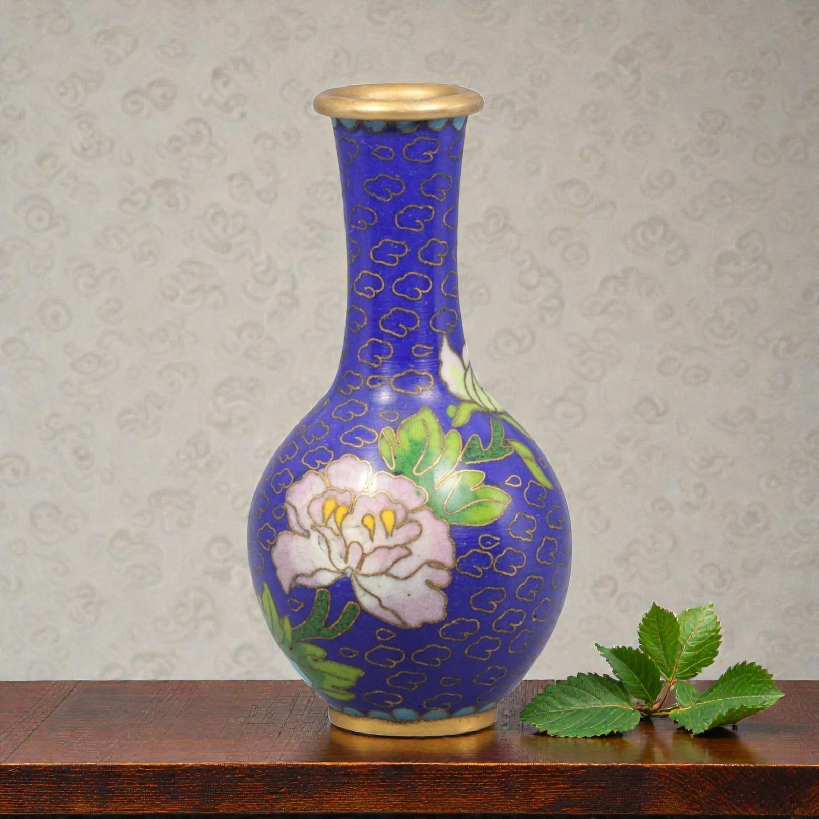A Chinese Cloisonne Enamel Vase, 20th Century, 82YC: Constructed from a copper alloy body and decorated with cloisonne enamel, the vessel is of baluster form with a rounded body rising to a tall, slightly flared neck and a gilt metal rim. The surface is