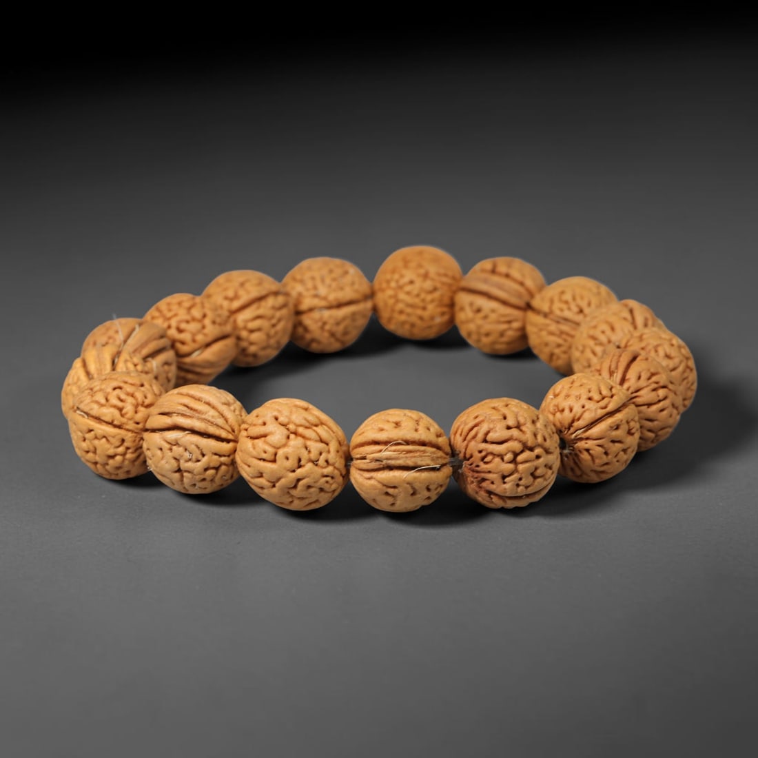 Rudraksha Seed Bracelet - Carved Buddhist Prayer Bead Strand, 63YM: This strand is constructed from naturally textured rudraksha seed beads, shaped into uniform barrel forms with intricate organic fissuring across each surface. The seeds display a consistent pale tan 