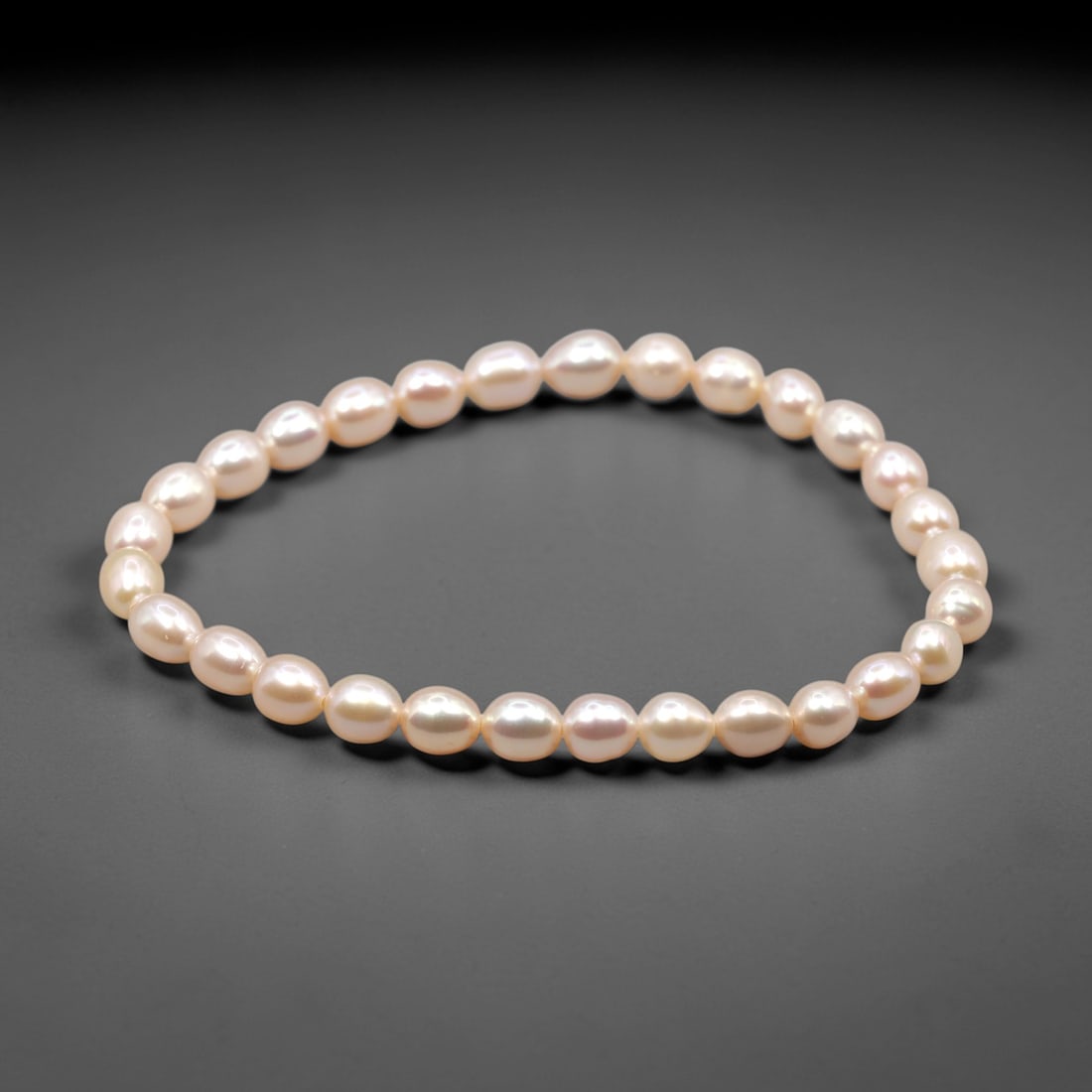 A Natural Freshwater Cultured Pearl Bracelet, 90ZH: Composed of baroque freshwater pearls strung in a single continuous strand to form a bracelet, with an internal circumference of 5.8 cm. The pearls exhibit a consistent oval to button shape across the