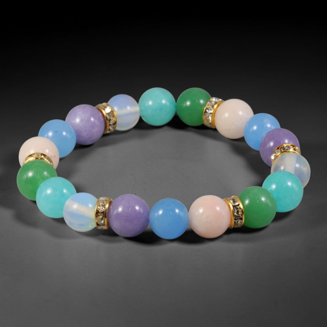 Natural Mixed Stone Beaded Bracelet - Polished Round Bead Strand, 40YM: This elastic stretch bracelet is constructed from uniformly spherical polished natural mineral beads separated by gold-toned metal spacers set with clear crystalline accents. The hard stone displays v