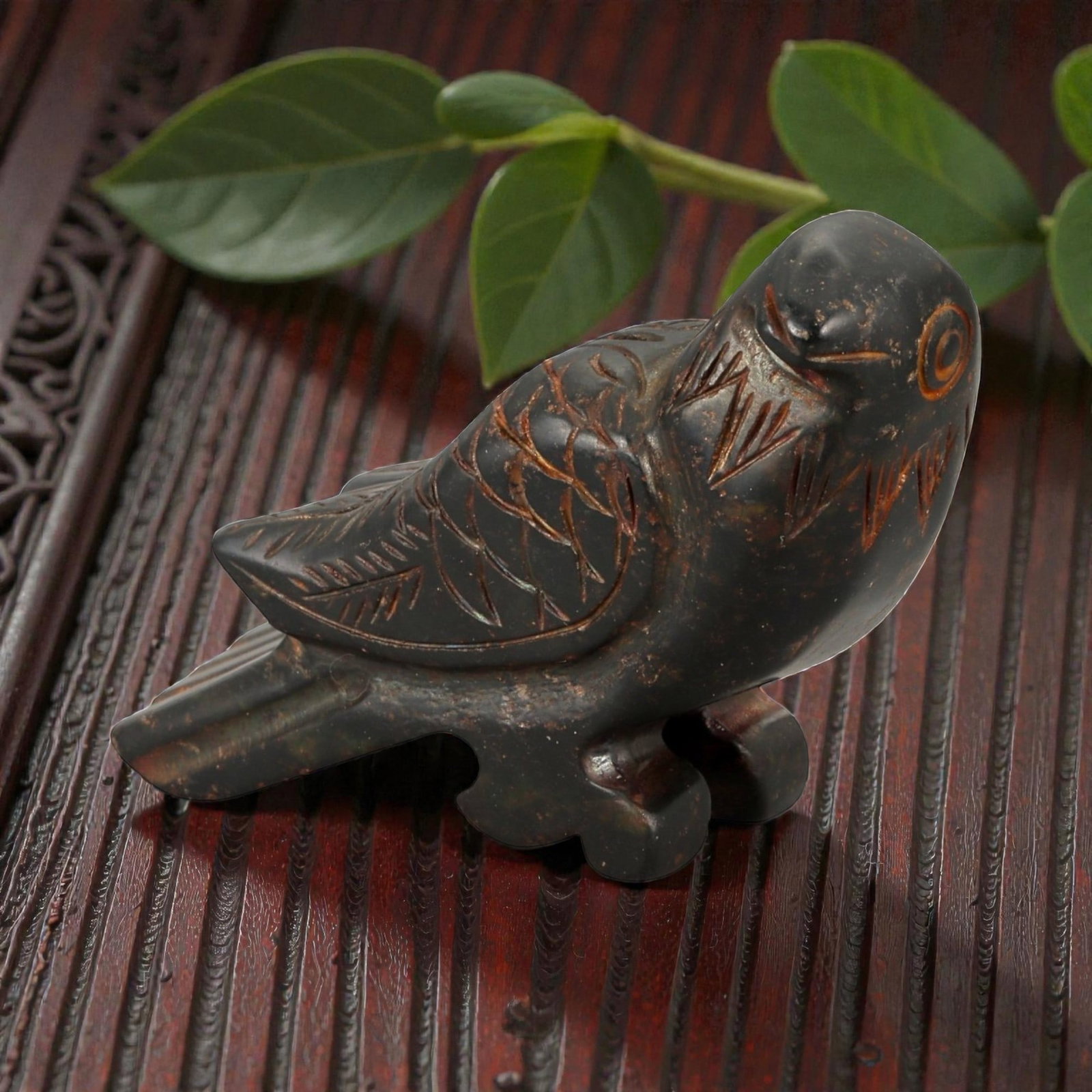 A Chinese Hardstone Bird Carving, 20th Century, 24YB: Carved from dark hardstone with a smooth, polished surface and scattered reddish-brown inclusions, the sculpture represents a stylized bird shown in a recumbent posture. The head is rendered with a ro