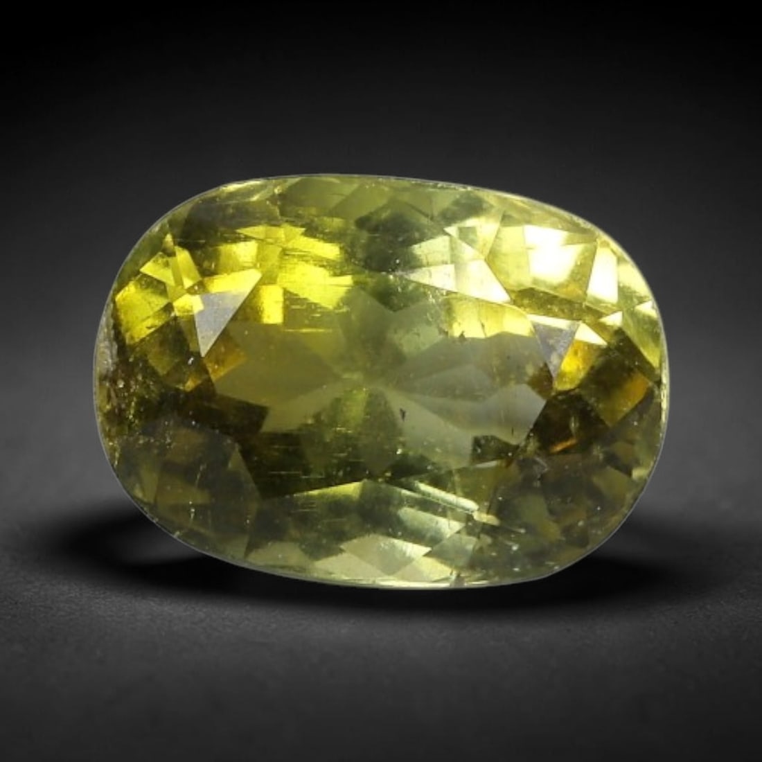 1.23 Carats Golden Yellow-Green Tourmaline Oval Cut - Natural Loose Gemstone, 65XC: This vibrant oval-cut tourmaline features a warm golden yellow-green hue, evoking the glow of sunlight filtering through sunlit foliage. Its faceting creates a lively play of light, with subtle color 
