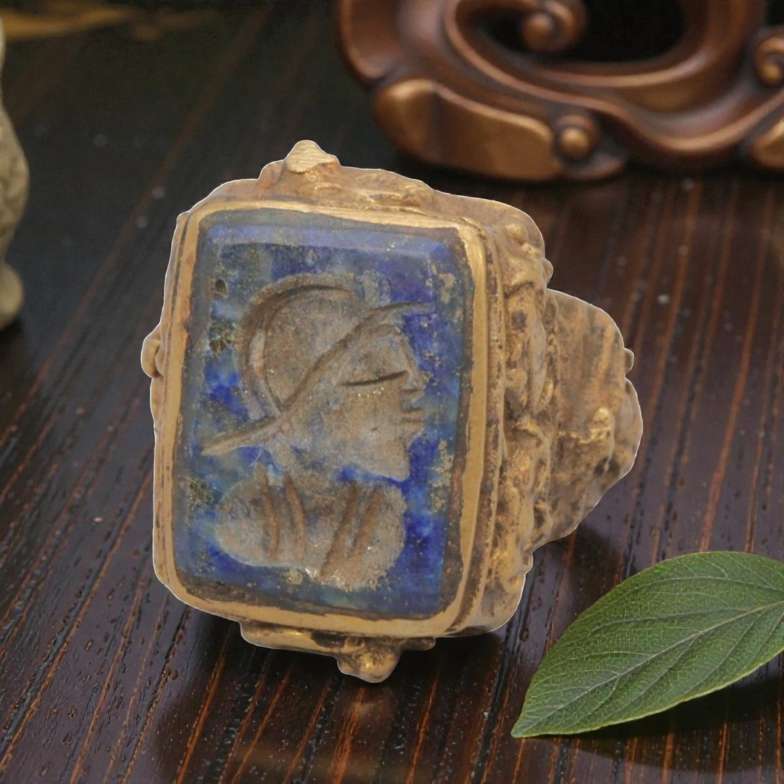 Antique Qajar Dynasty Gilt Intaglio Ring, US Size 6.5, 84WS: This ring features a rectangular lapis lazuli intaglio carved with a profile bust of a figure wearing a headdress, executed in the glyptic style characteristic of Qajar period Iran. The rich blue lapi